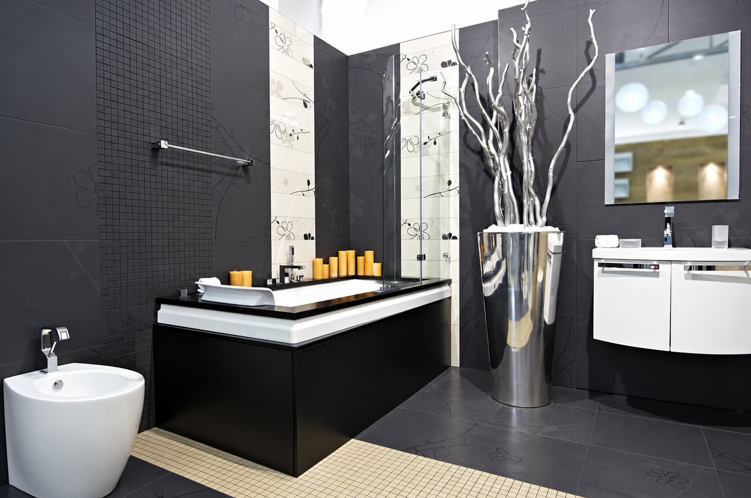 Salle de bain contemporaine aux murs gris anthracite avec baignoire noire et blanche, bidet, meuble vasque blanc suspendu, miroir et grand vase argenté orné de branches.